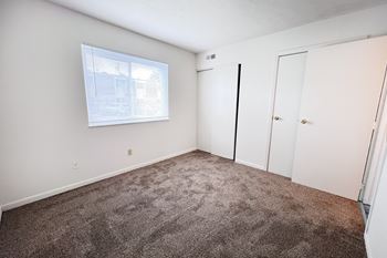 A room with a carpeted floor and a window with blinds.